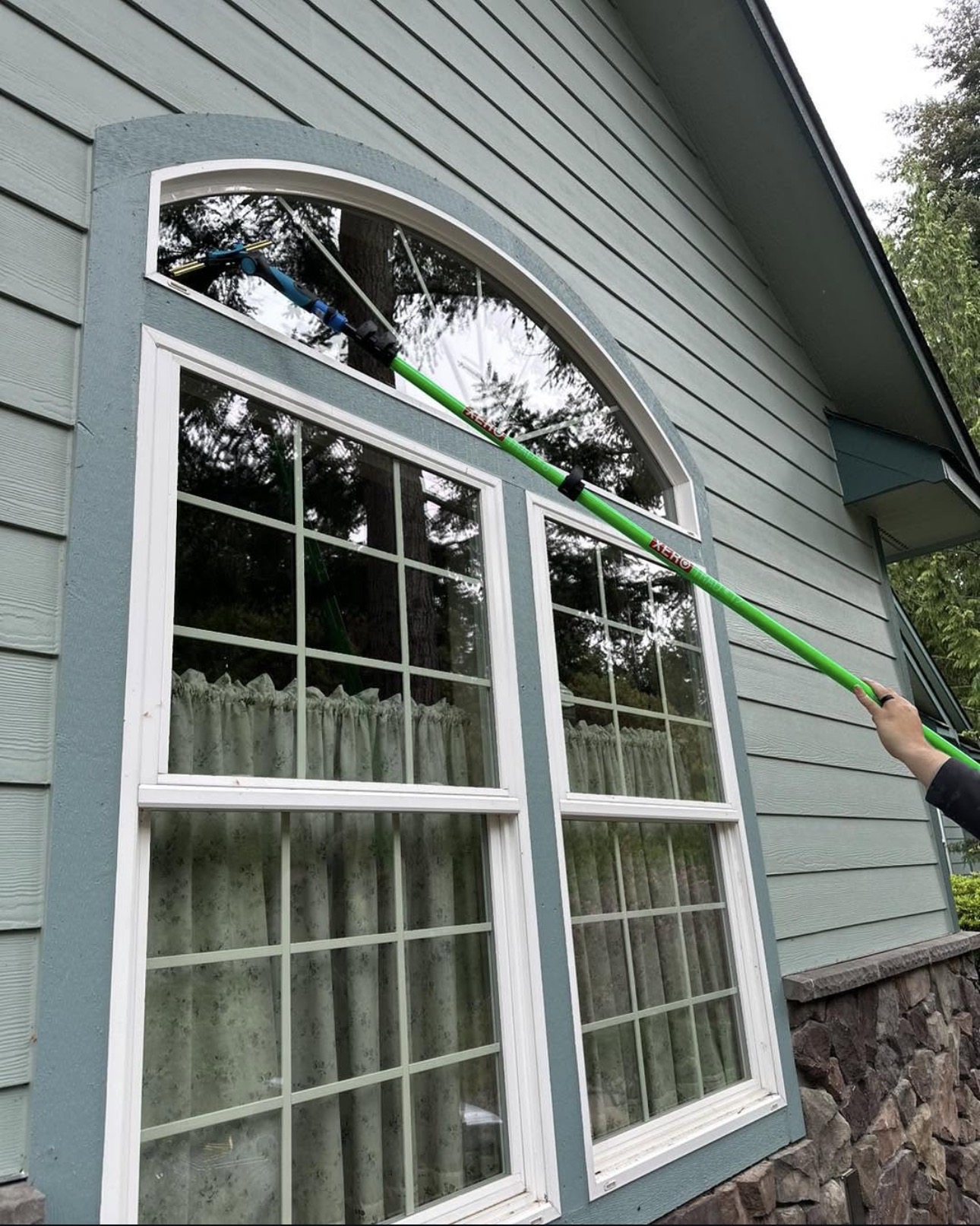Cleaning a second-story arched window with an extension pole