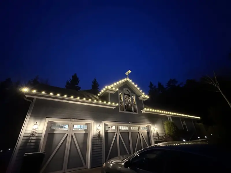 A garage and home roofline lit for Christmas at dusk